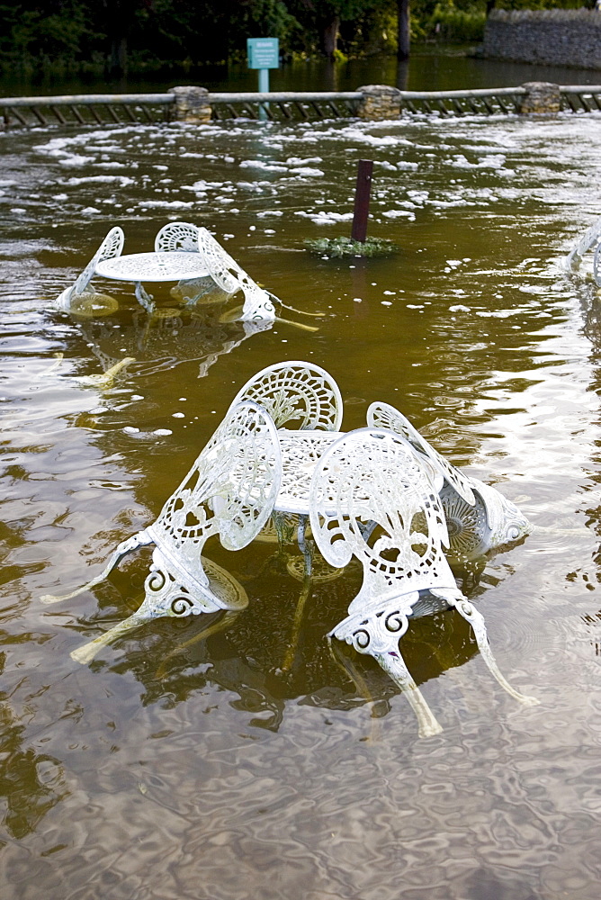 Outdoor tables and chairs of The Swan Hotel submerged in flood water, Minster Lovell, Oxfordshire, United Kingdom