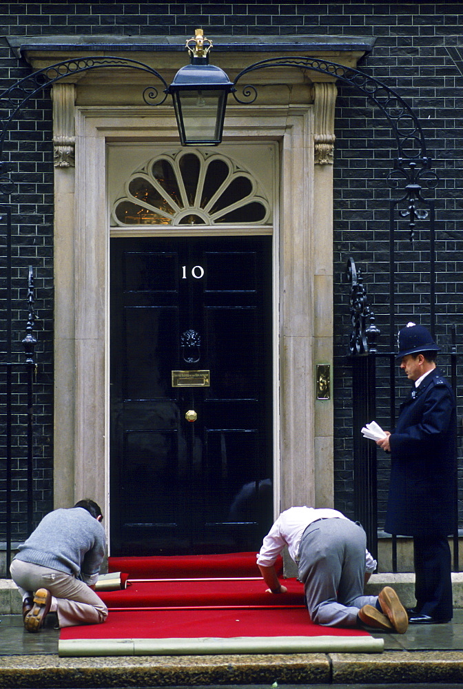 Policeman watches  red carpet being laid outside number 10 Downing Street, the home of the Prime Minister, London, UK.