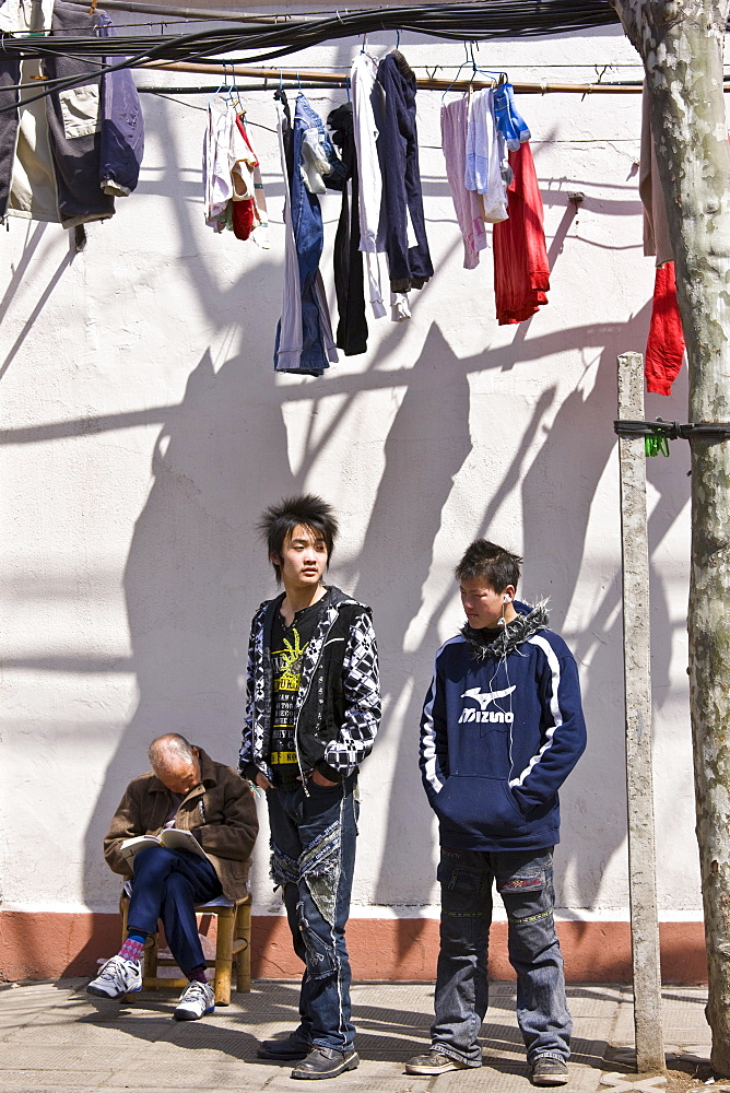 Teenagers stand by a man sleeping in Zi Zhong Road, old French Concession Quarter in Shanghai, China