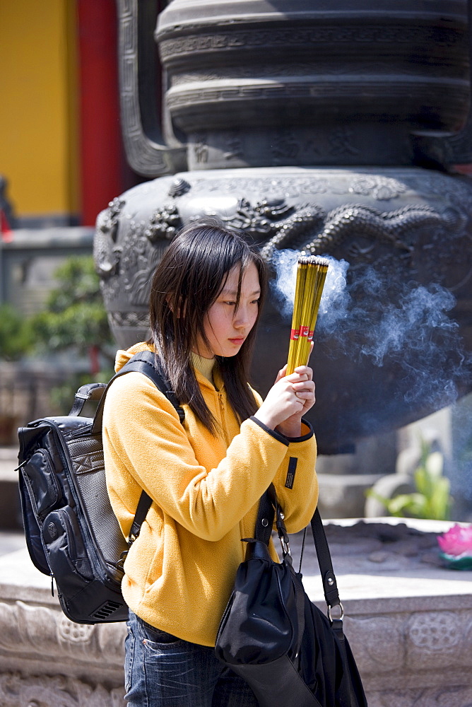 Worshipper burning incense at the Jade Buddha Temple, Shanghai, China