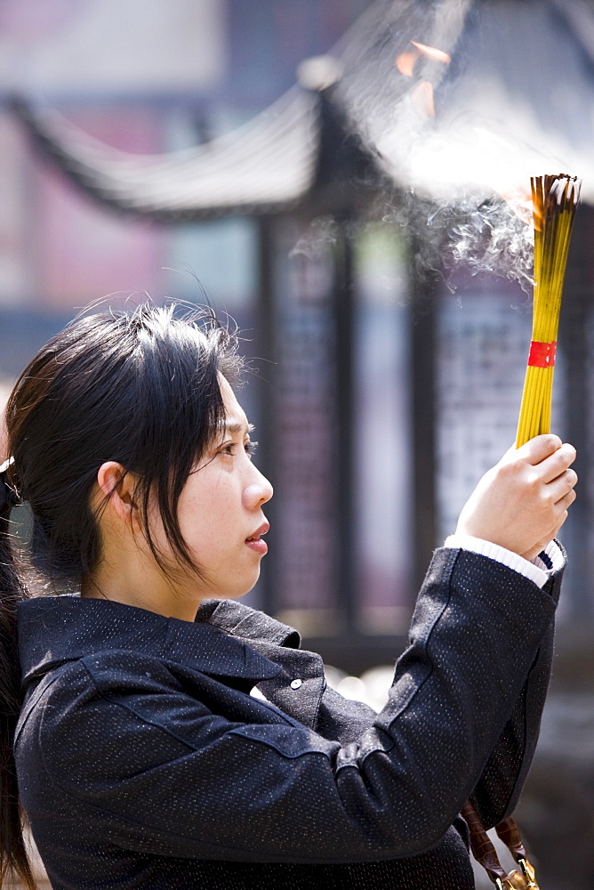 Worshipper burning incense at the Jade Buddha Temple, Shanghai, China