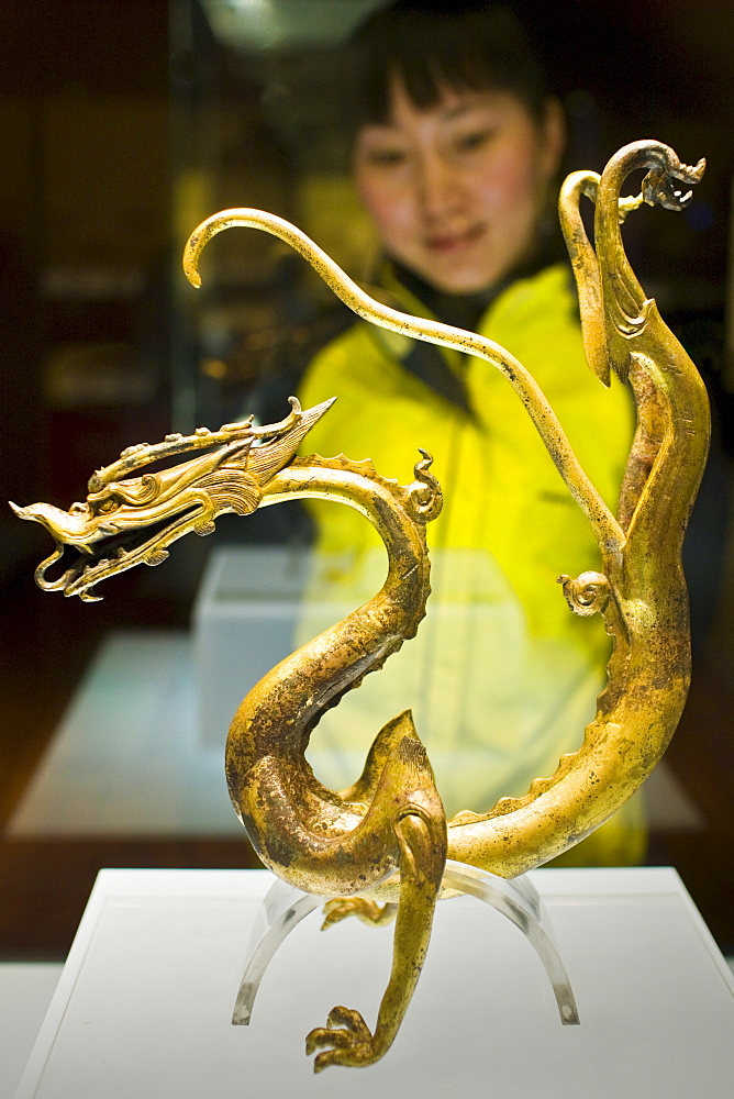 Visitor look at a Chinese dragon ornament on display in glass case in the Shaanxi History Museum, Xian, China