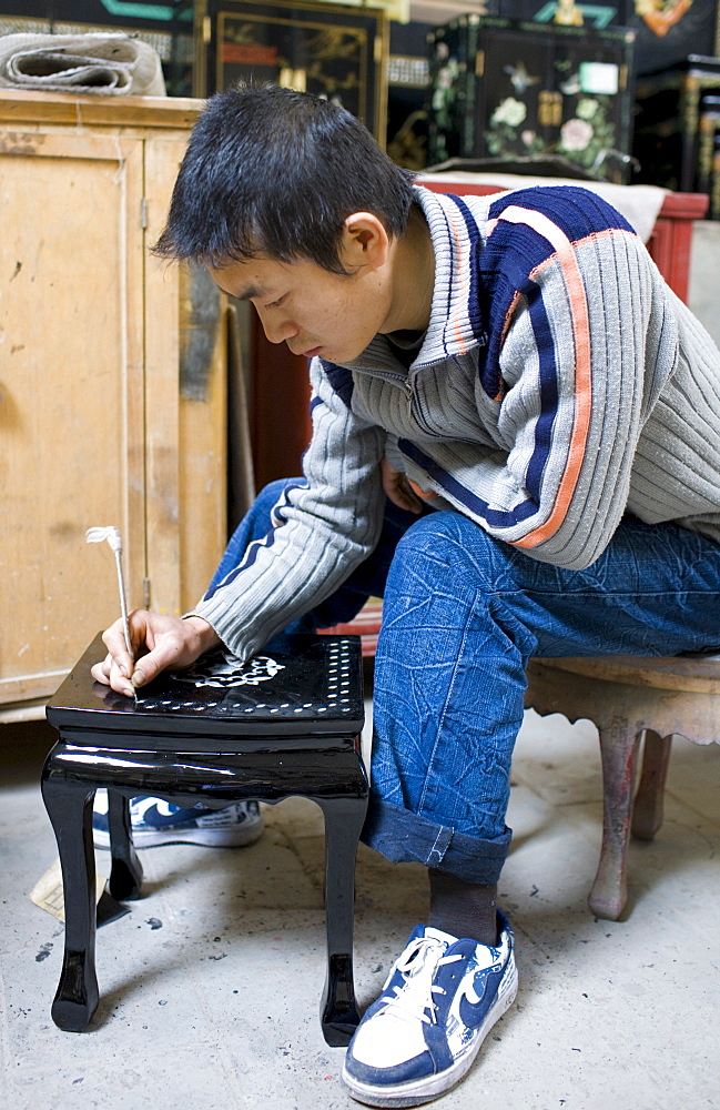 Marquetry craftsman at work on lacquer table at souvenir and furniture factory, Xian, China