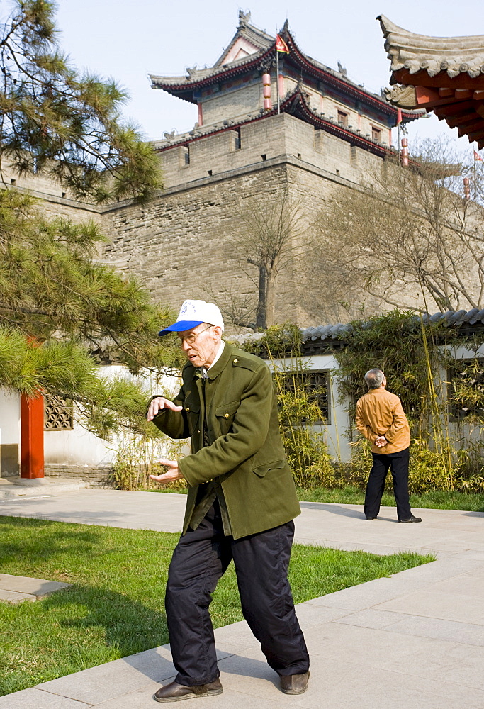 Man practises Tai chi as part of his morning exercise in the park by the City Wall of Xian, China