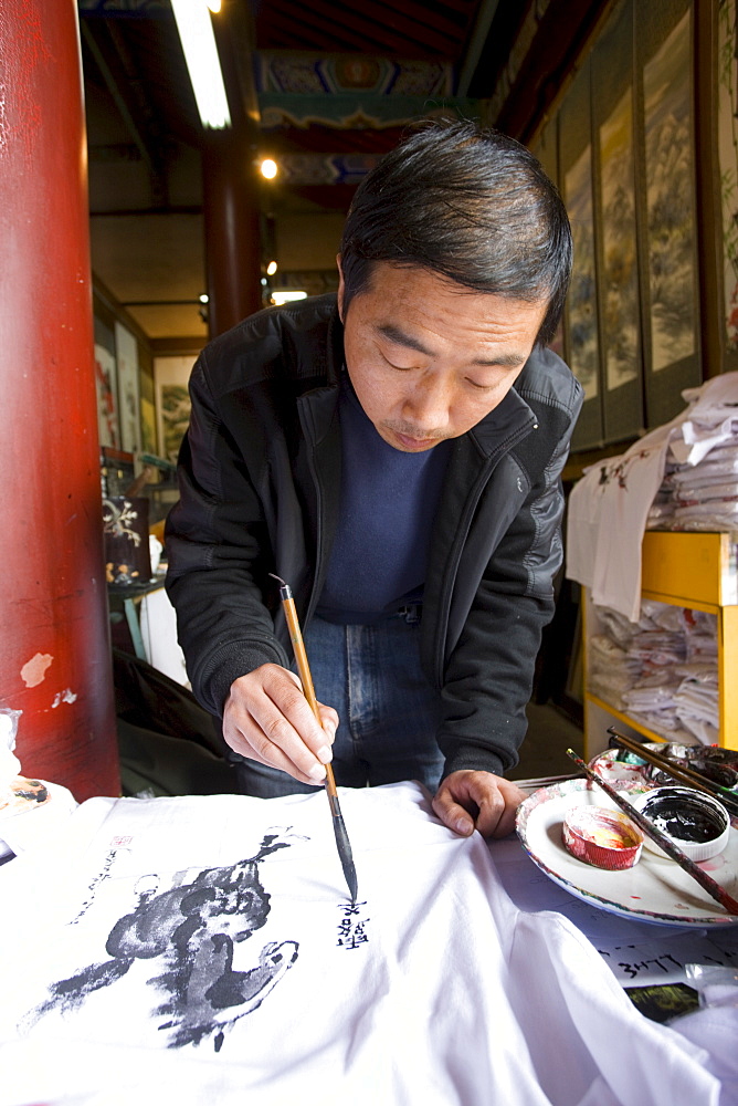 Traditional Chinese artist at work on souvenirs at Small Wild Goose Pagoda gift shop, Xian, China