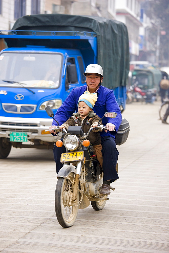 Man and child on a motorbike on market day in the town of Baisha, near Guilin, China