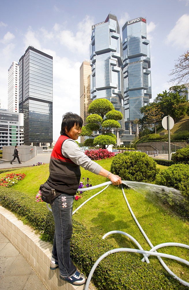 Gardener watering grass in the financial district by the Lippo Centre, Hong Kong, China