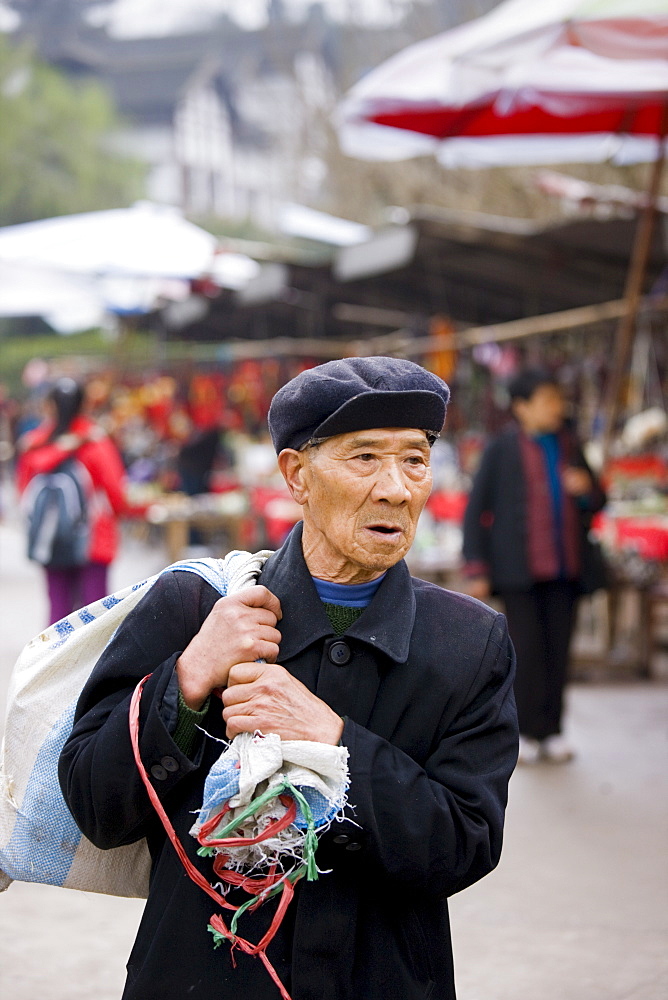 Elderly Chinese man carrying sack through Chongqing, China