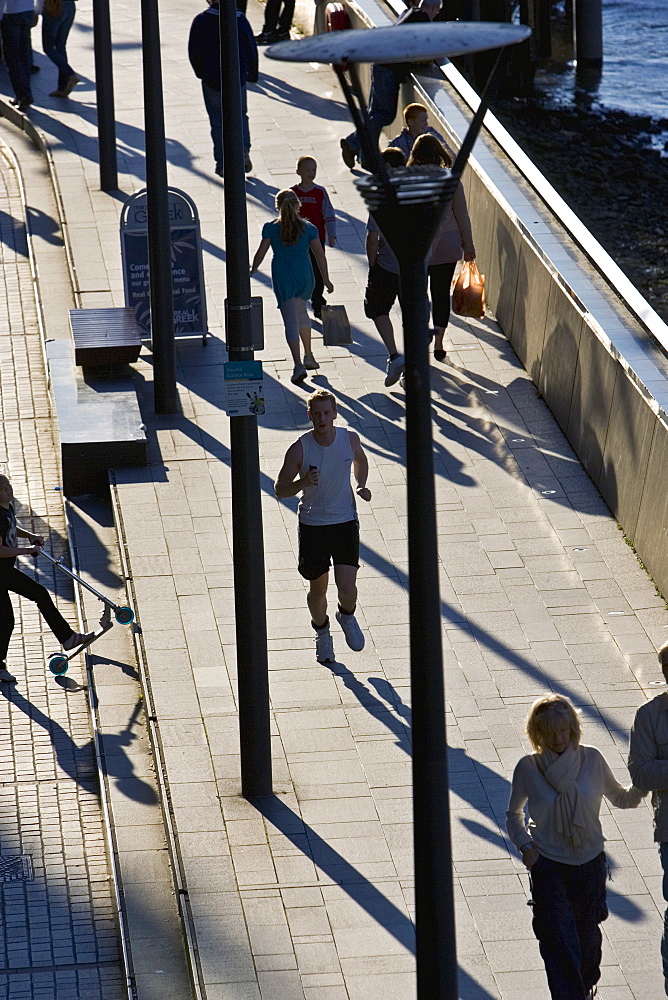 Pedestrians and jogger on Thames Path, London, England, United Kingdom