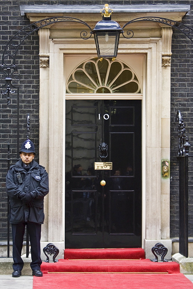 Armed policeman guards Number 10 Downing Street, official home of the British Prime Minister, London, UK