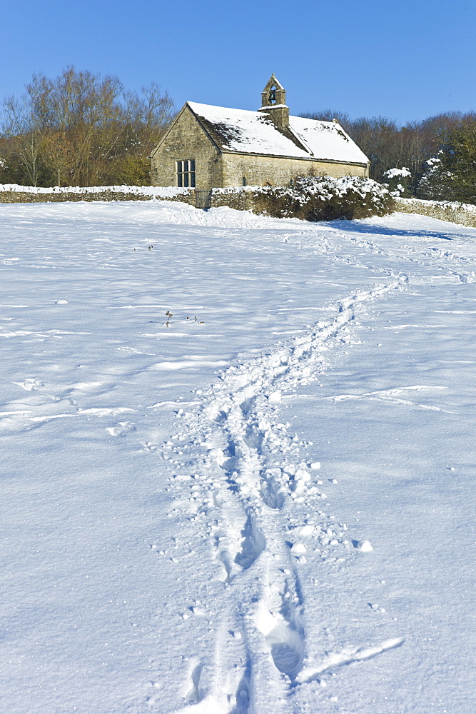 Quaint 13th Century chapel in snow-covered Windrush valley at Widford, The Cotswolds, UK