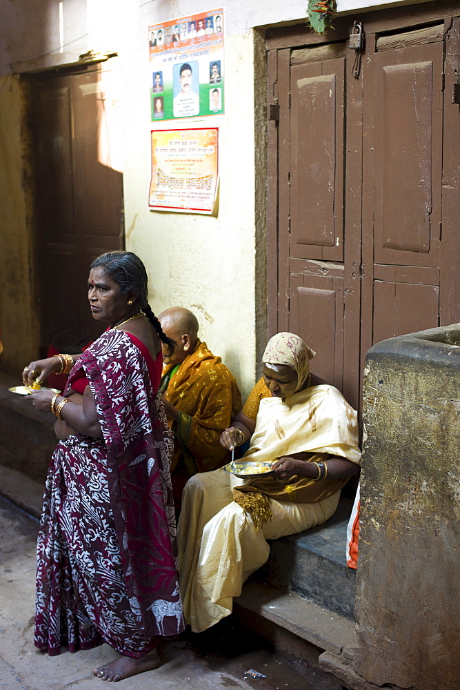 Indian people having lunch in an alleyway in the holy city of Varanasi, Benares, Northern India