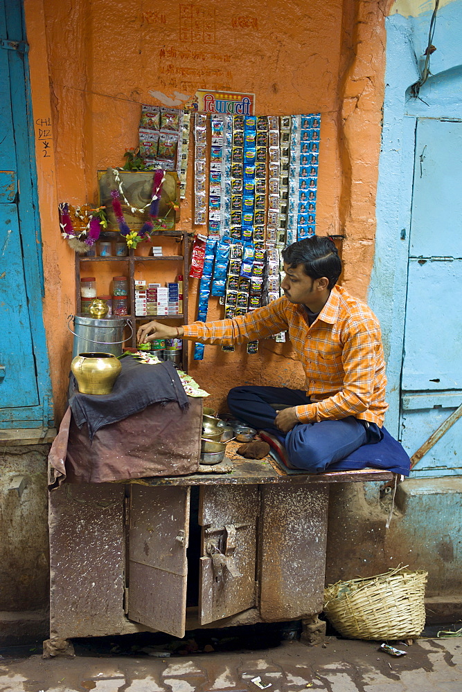 Indian man runs market stall in alleyway in the city of Varanasi, Benares, Northern India