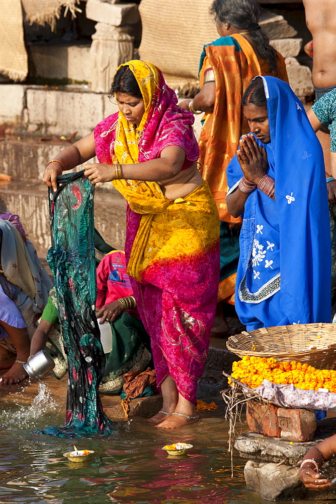 Indian Hindu pilgrims washing clothes and bathing in The Ganges River at Dashashwamedh Ghat in Holy City of Varanasi, India