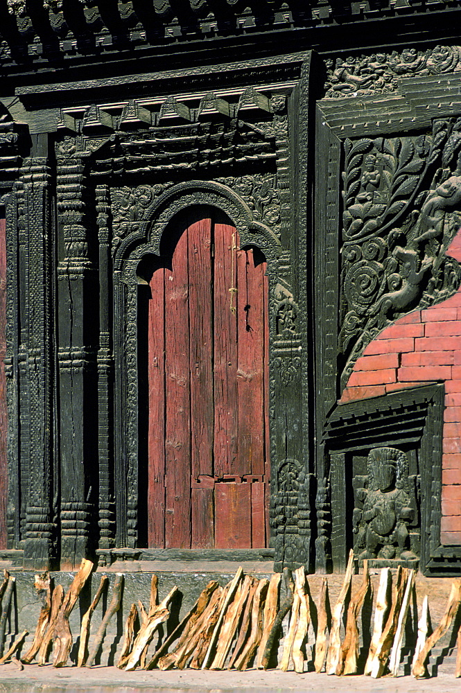 Firewood drying near ornate carved wooden doorway, Bhaktapur, Nepal