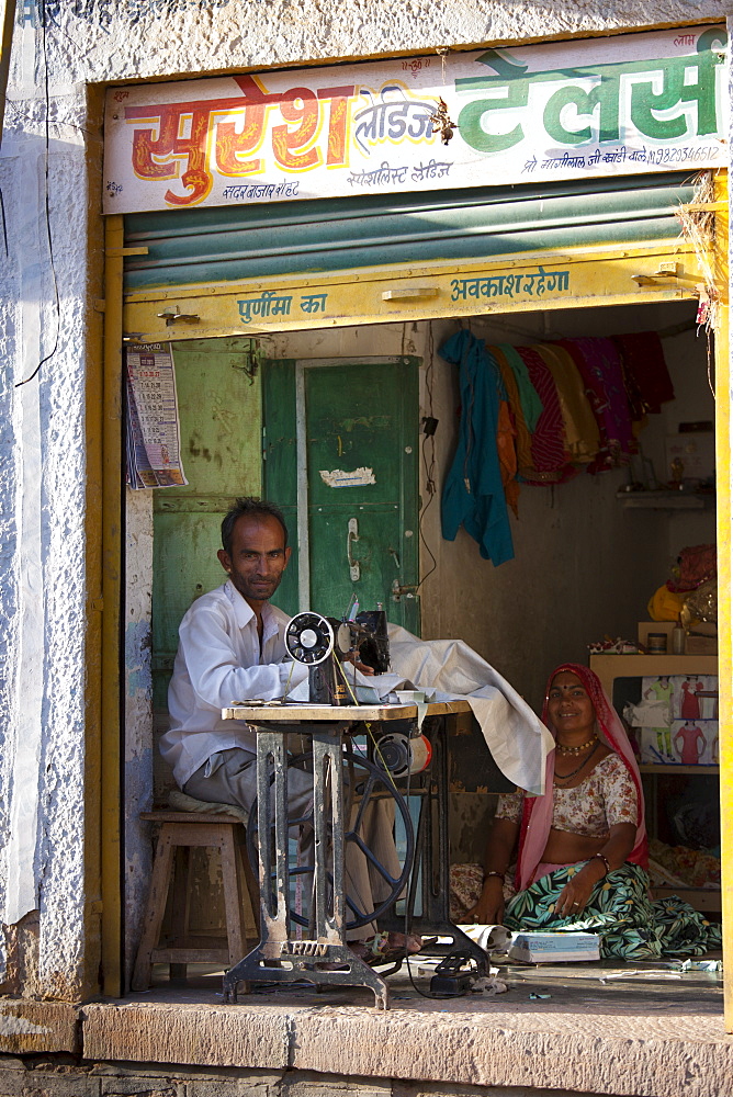 Indian man and wife sewing fabric in village of Rohet in Rajasthan, Northern India