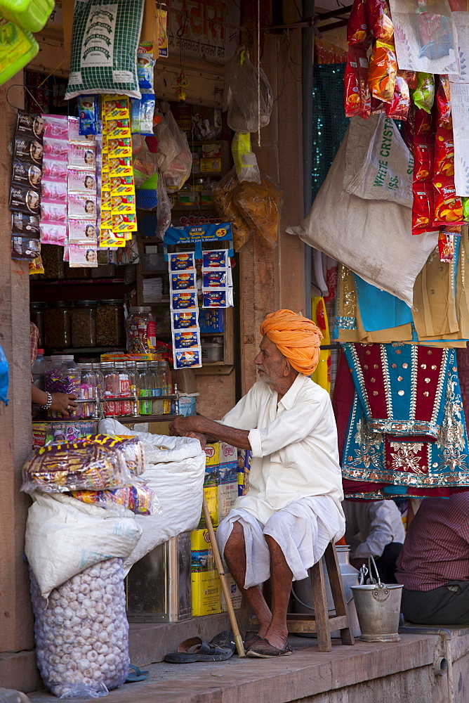 Indian shopkeeper in his food shop and general store in village of Rohet in Rajasthan, Northern India