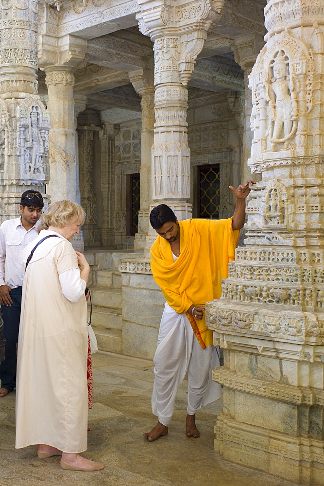 Temple priest shows tourists stone carving detail at The Ranakpur Jain Temple at Desuri Tehsil in Pali District of Rajasthan, India