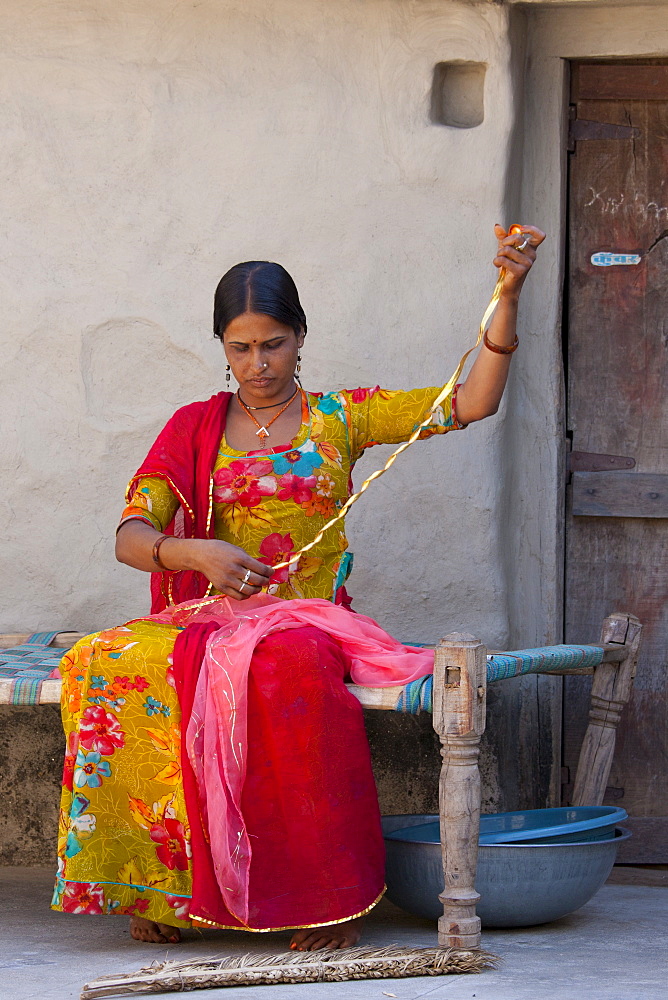 Young Indian Hindu girl sewing bridal veil at home in Tarpal in Pali District of Rajasthan, Western India