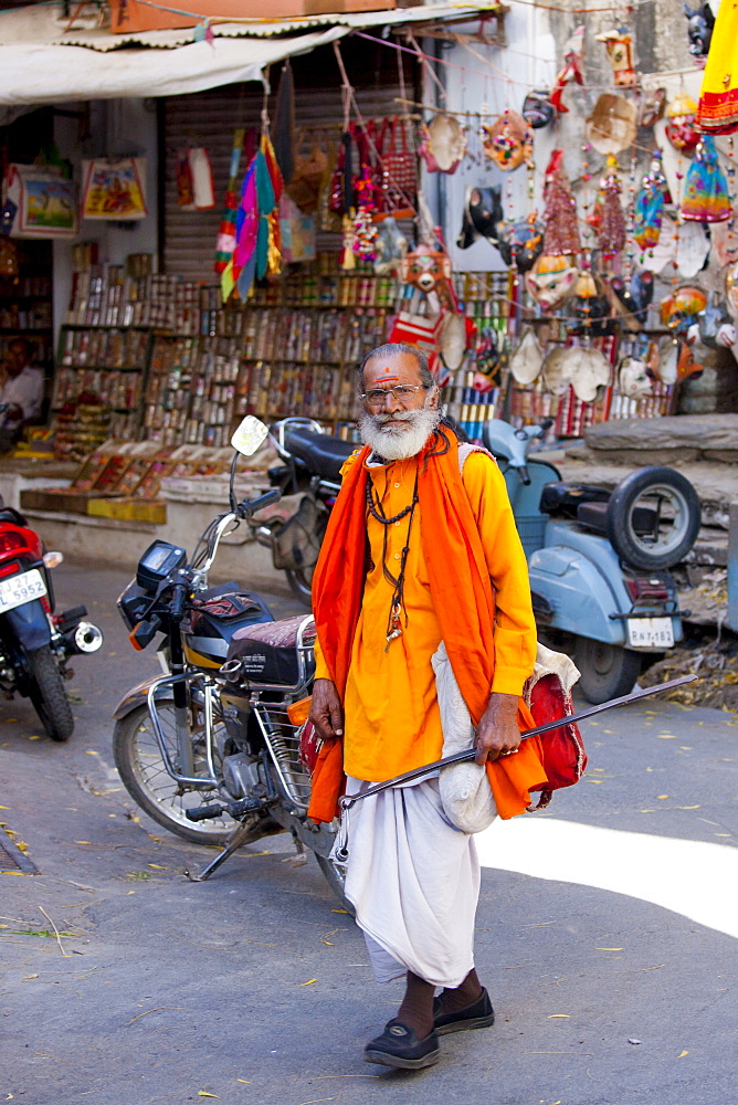 Hindu sadhu holy man wearing traditional robes walks in old town in Udaipur, Rajasthan, Western India