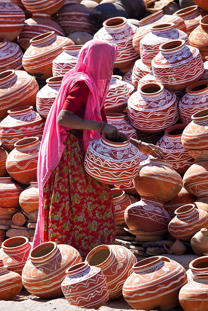 Indian woman selling clay water pots on sale in old town Udaipur, Rajasthan, Western India,