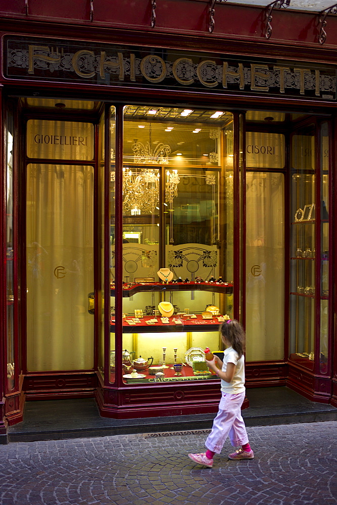 Young girl gazes at jewels in Fratelli Chiocchetti jewellery shop in Via Fillungo,  Lucca, Italy