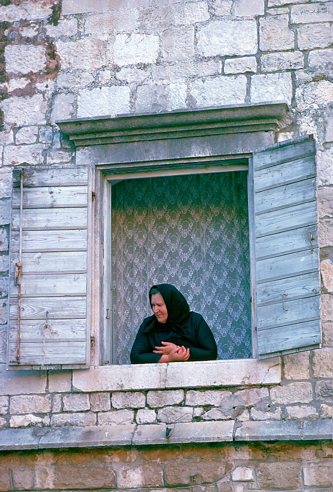 A woman watching from her window in Kotor, Montenegro, - formerly Yugoslavia - a UNESCO World Heritage Site.