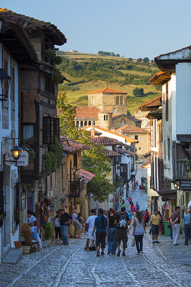 Tourists walk past medieval buildings along cobbled street of Calle Del Canton in Santillana del Mar, Cantabria, Northern Spain