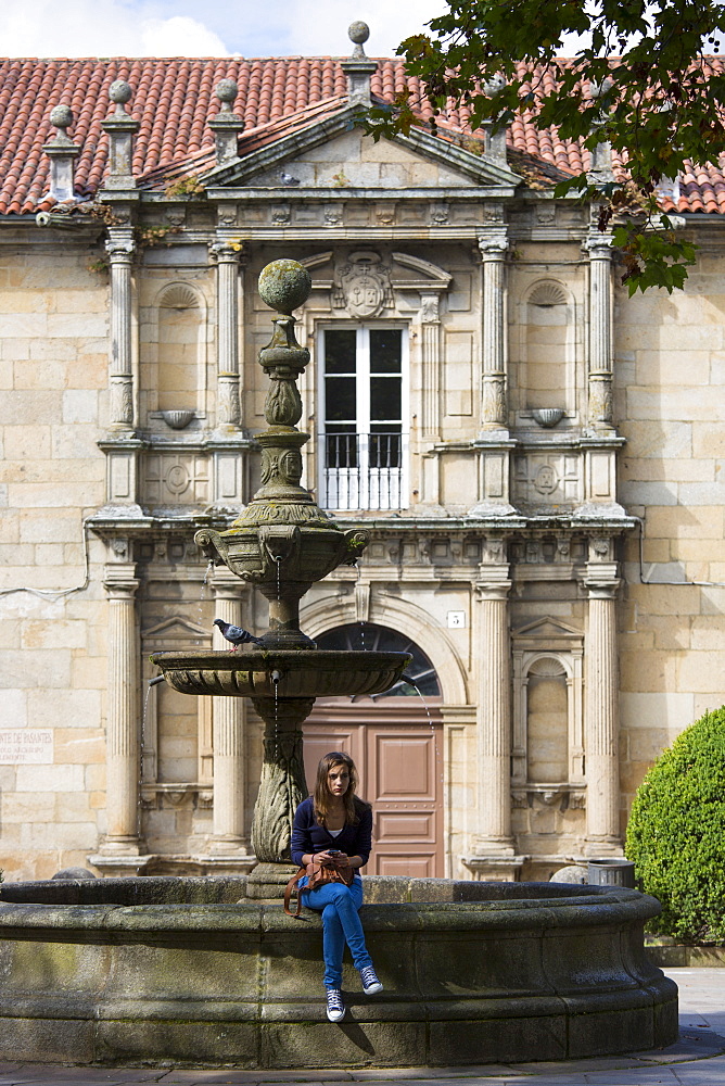 Spanish girl by fountain at Colexio de San Clemente de Pasantes in Santiago de Compostela, Galicia, Spain