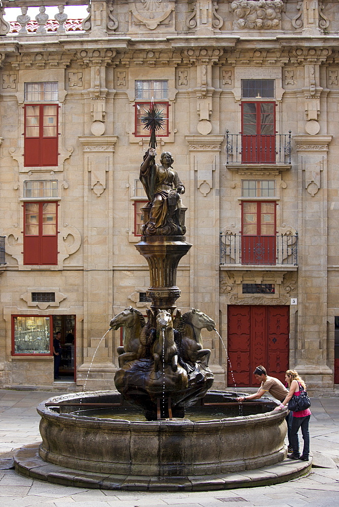 Young couple at Dos Cavalos fountain of horses, Praza das Praterias, in Santiago de Compostela, Galicia, Spain