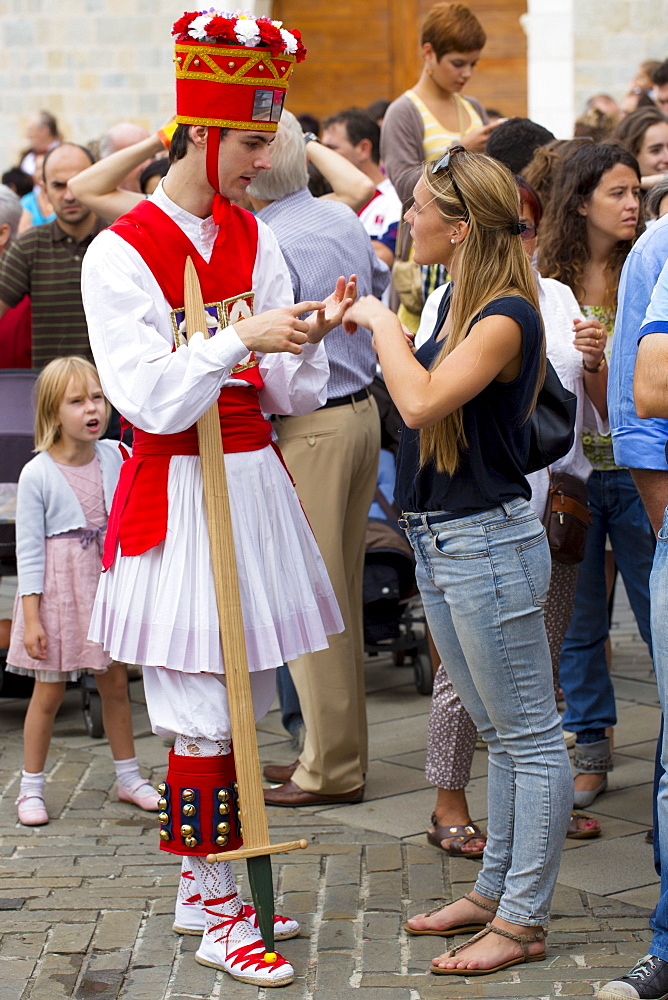 Dancer in costume chats with woman in casuals at San Fermin Fiesta at Pamplona, Navarre, Northern Spain