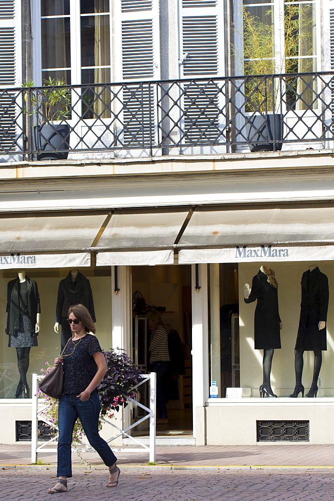 Stylish French woman passes Max Mara boutique shop in the fashionable area of Pau in the Pyrenees, France