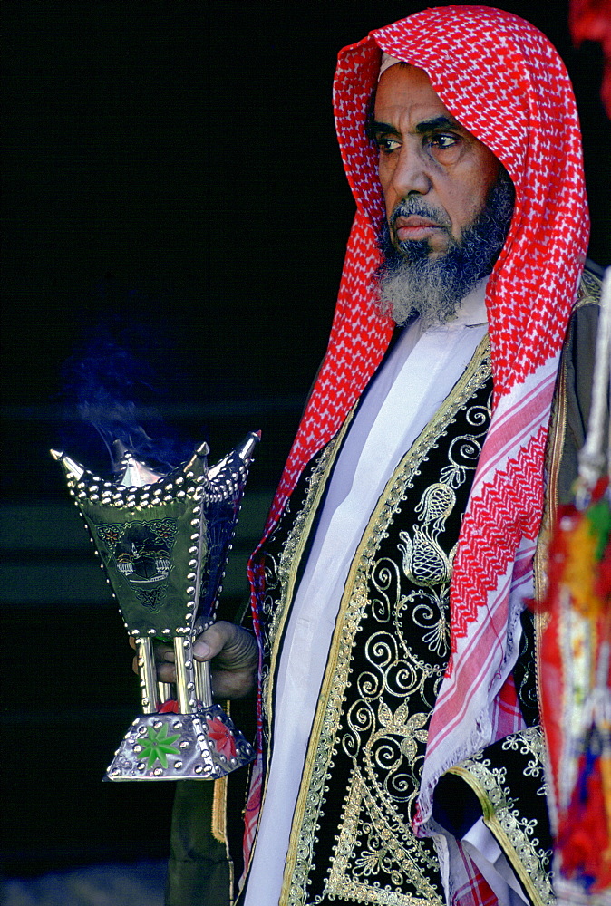 Bedouin man holding a smoking incense burner, Saudi Arabia