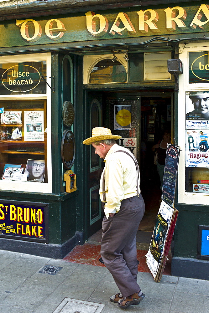 Man walking past de Barra bar in Timoleague, West Cork, Ireland