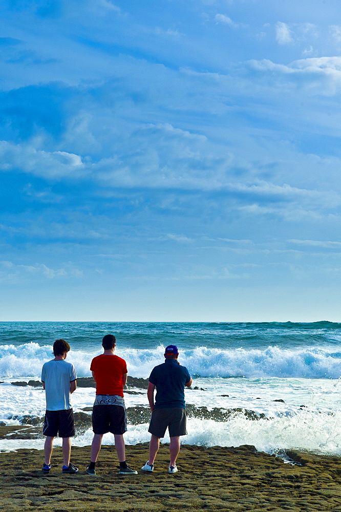 Young men looking out to sea watching the waves breaking, Doolin, County Clare, West Coast of Ireland