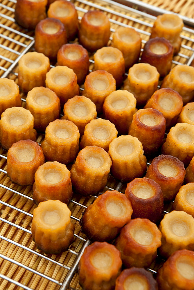 Freshly-baked French Bordeaux speciality canele cakes on sale at food market in Bordeaux region of France