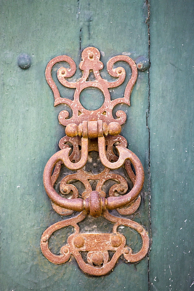 Door knocker design on green painted wooden door in Bourdeilles near Brantome, Northern Dordogne, France