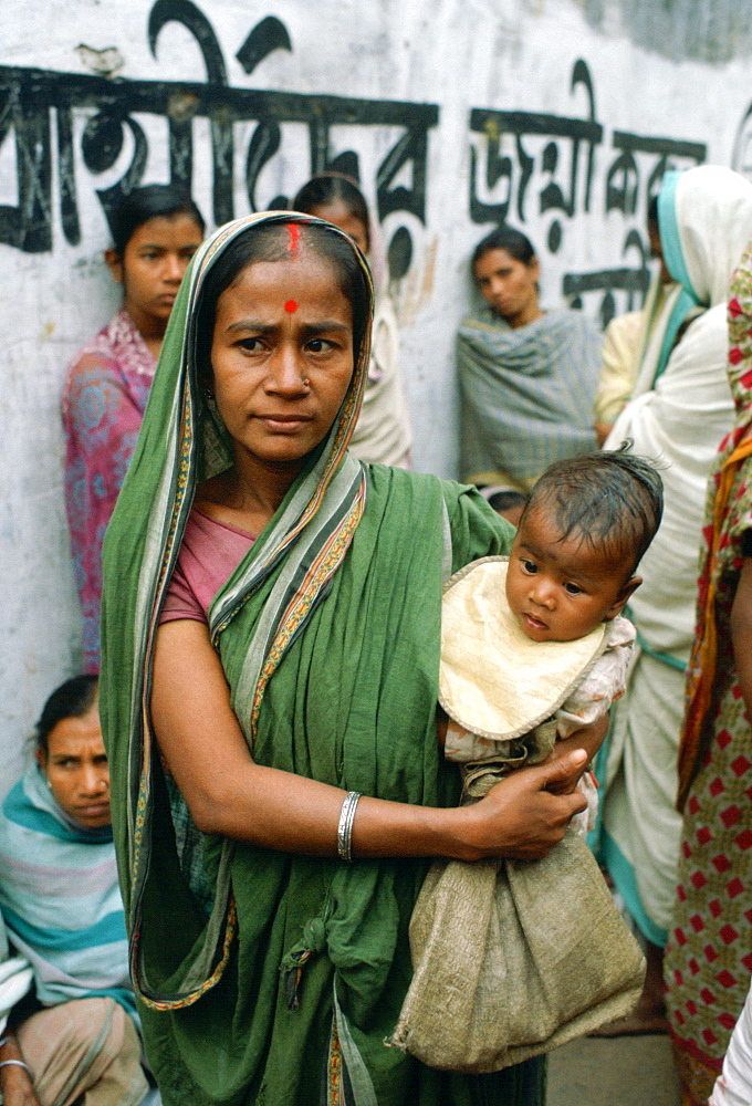 A mother carrying her child  and queuing for food handouts withother women at Mother Teresa's Mission in Calcutta,  India