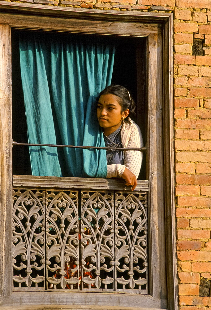 Young woman at carved window in Patan, Nepal