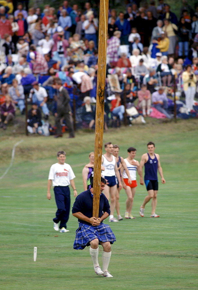 Scottish strongman in tartan kilt tossing the caber at the Braemar Royal Highland Gathering, the Braemar Games in Scotland