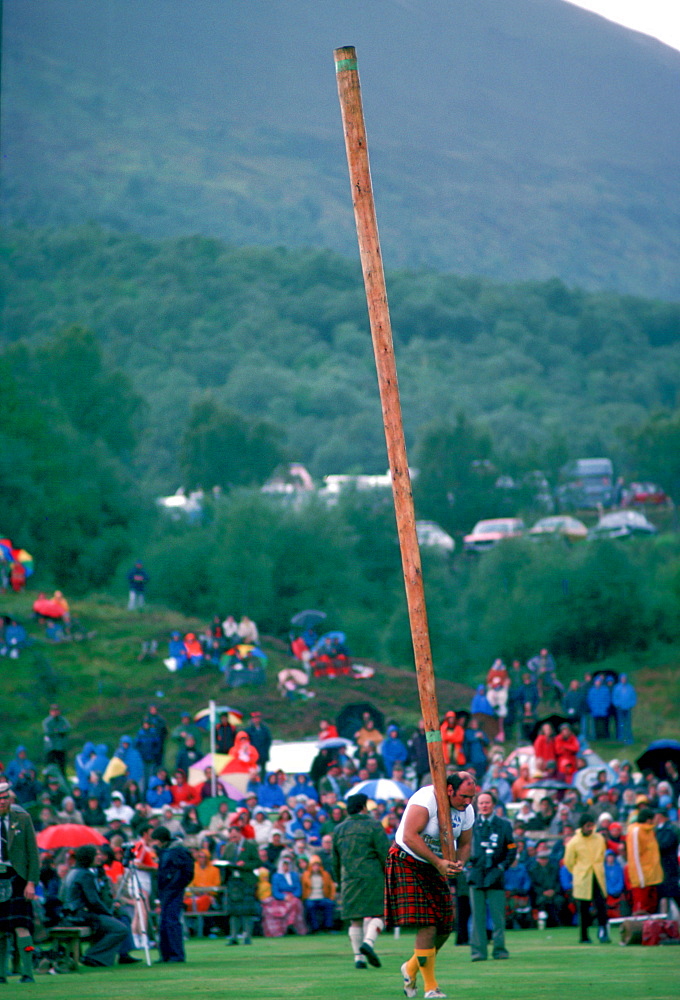 Tossing the Caber test of strength at the Braemar Games highland gathering in the rain  in Scotland.