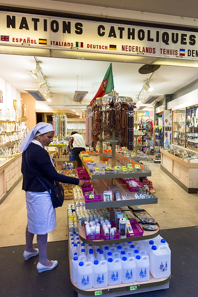 Religious icons, holy water and statues on sale at souvenir shops at pilgrimage location of Lourdes, Pyrenees, France, Europe