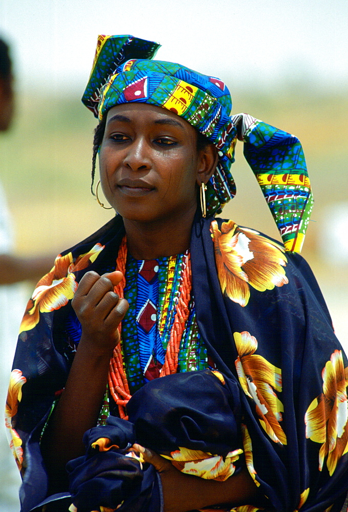 Nigerian woman in brightly coloured clothes and with the traditional face markings.