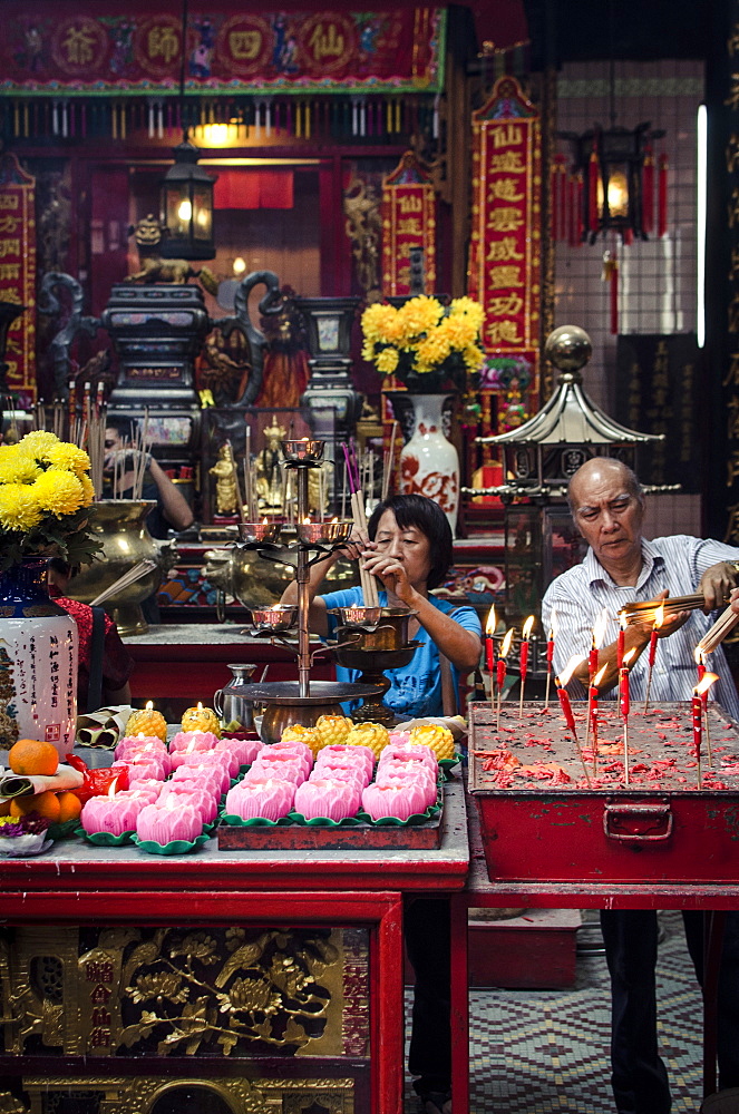 A man and women light incense sticks during Chinese New Year celebrations, Sze Ya Temple, Chinatown, Kuala Lumpur, Malaysia, Southeast Asia, Asia