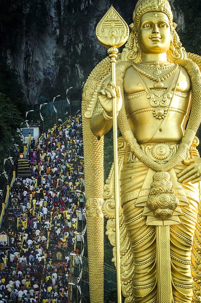 Devotees climb the steps to Batu Caves, overseen by a statue of Lord Murugan during Thaipusam, Batu Caves, Kuala Lumpur, Malaysia.