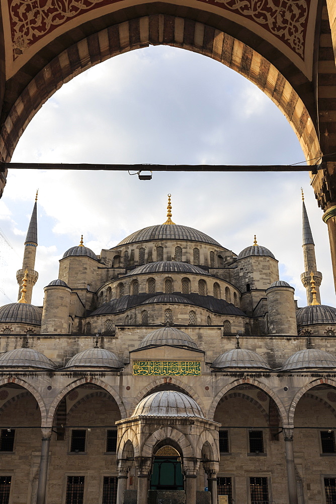 Blue Mosque under a partially cloudy sky through an ornate archway, golden August early morning, Sultanahmet, Istanbul, Turkey, Europe