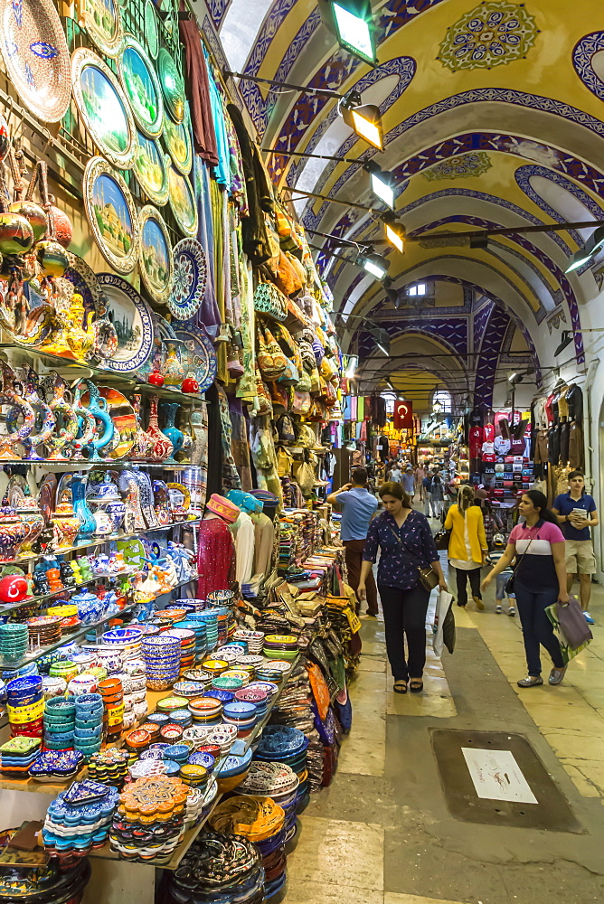 Shoppers with bags on a Friday afternoon in street with decorated ceiling and pottery stall, Grand Bazaar, Istanbul, Turkey, Europe