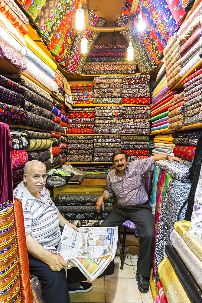 Sellers (vendors) of traditional Turkish fabrics seated in their shop reading a newspaper, Grand Bazaar, Istanbul, Turkey, Europe