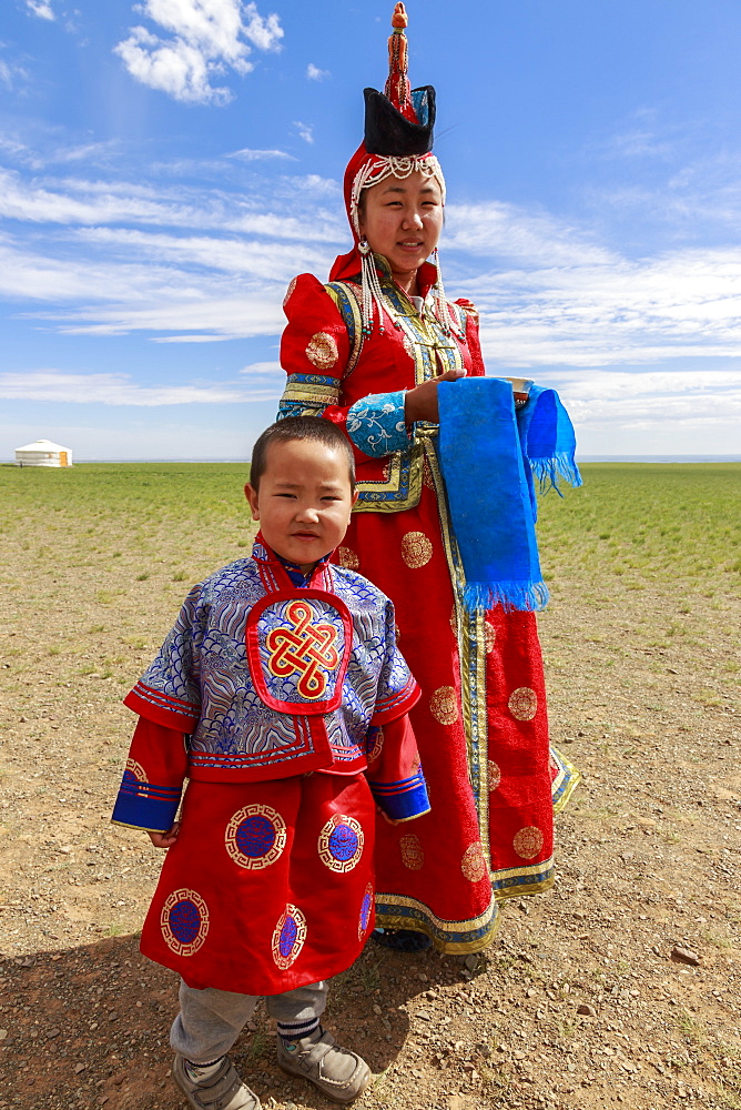 Woman and child in traditional dress (deel), silver bowl for milk greeting, near ger, Gobi desert, Bulgan, Omnogov, Mongolia, Central Asia, Asia