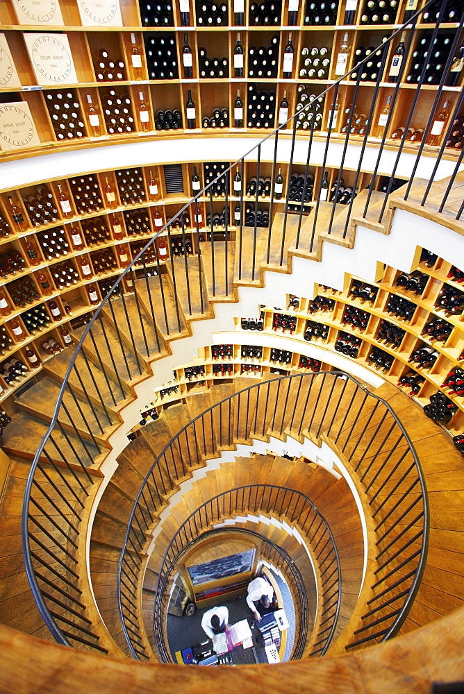 Spiral staircase with wine bottles kept on rack in L'Intendant wine shop, Bordeaux, France